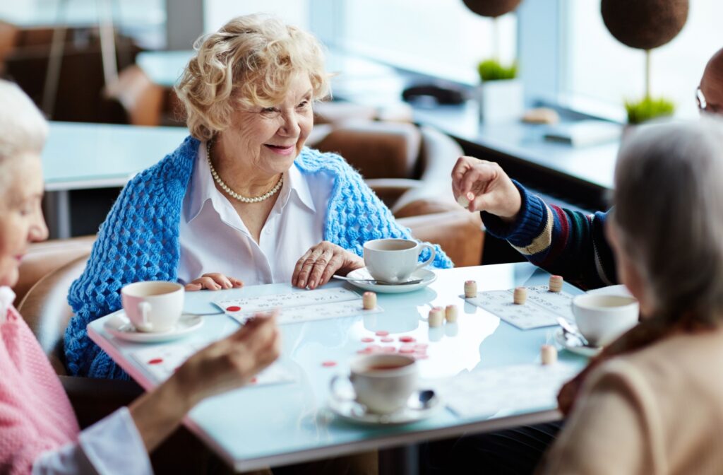 A group of older adult women playing a memory game together while drinking tea.