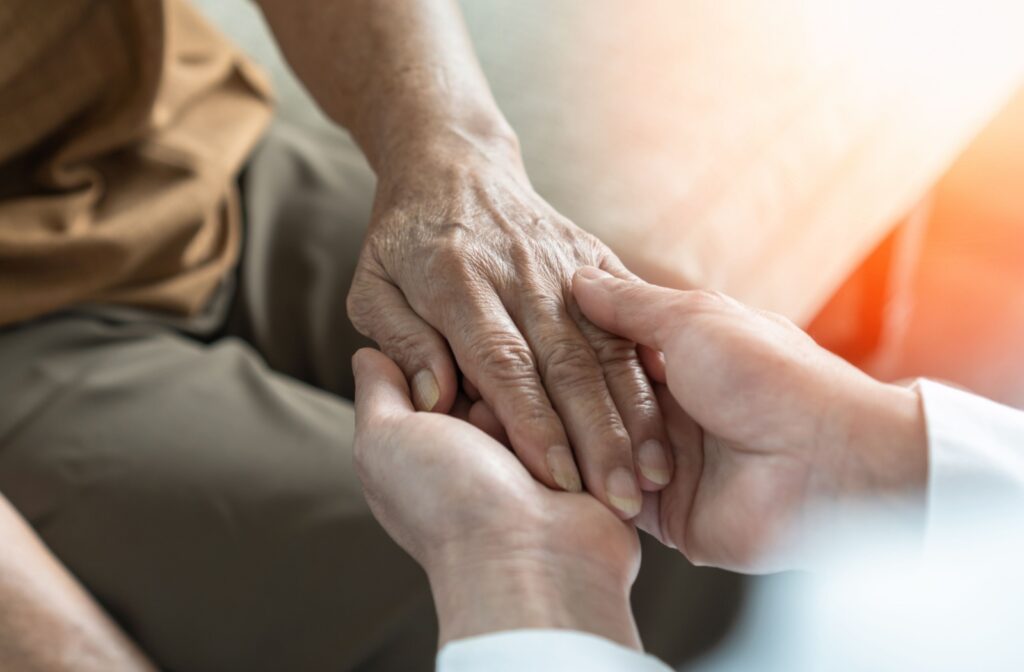 A doctor holds a senior patient's hand during a conversation of memory loss.