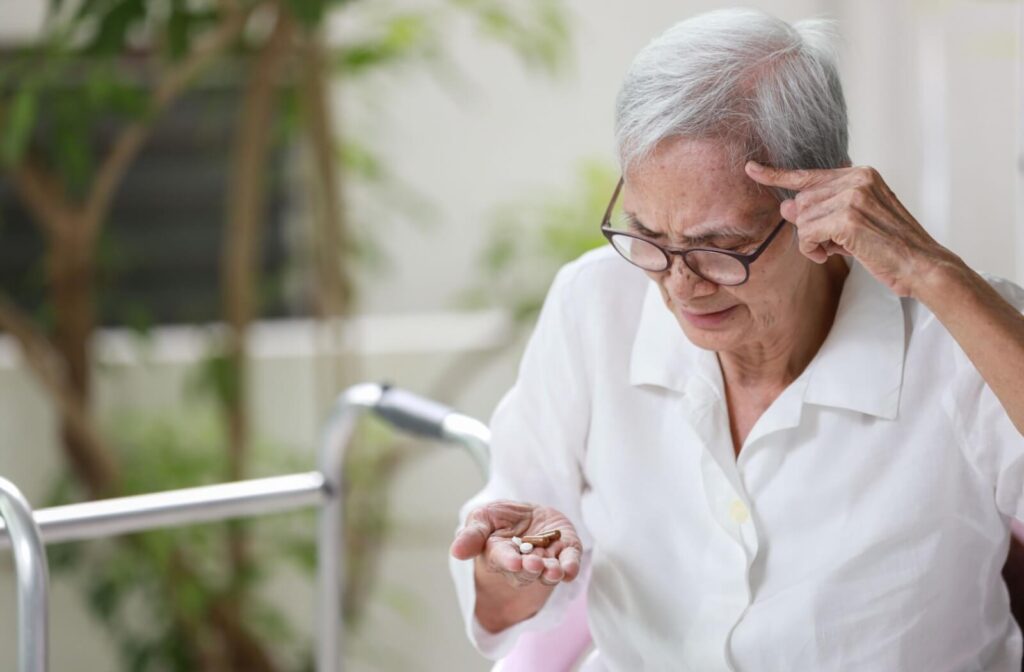 A senior holding pills tries to remember if they took their medication already.