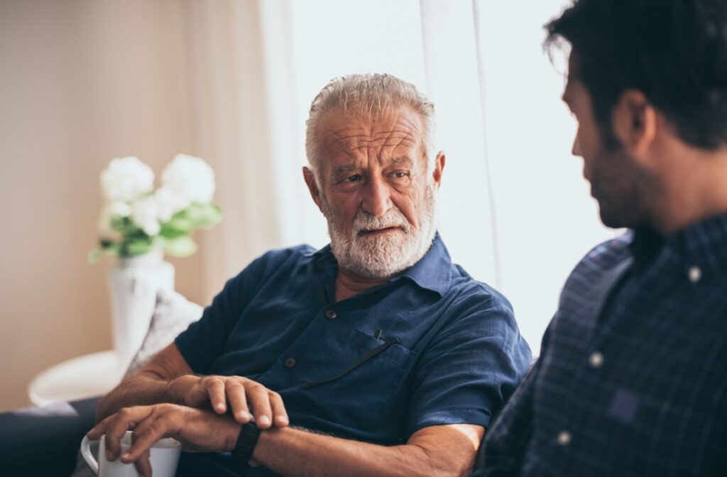 An older adult listens carefully as their adult child tries to calm them down during a conversation in memory care